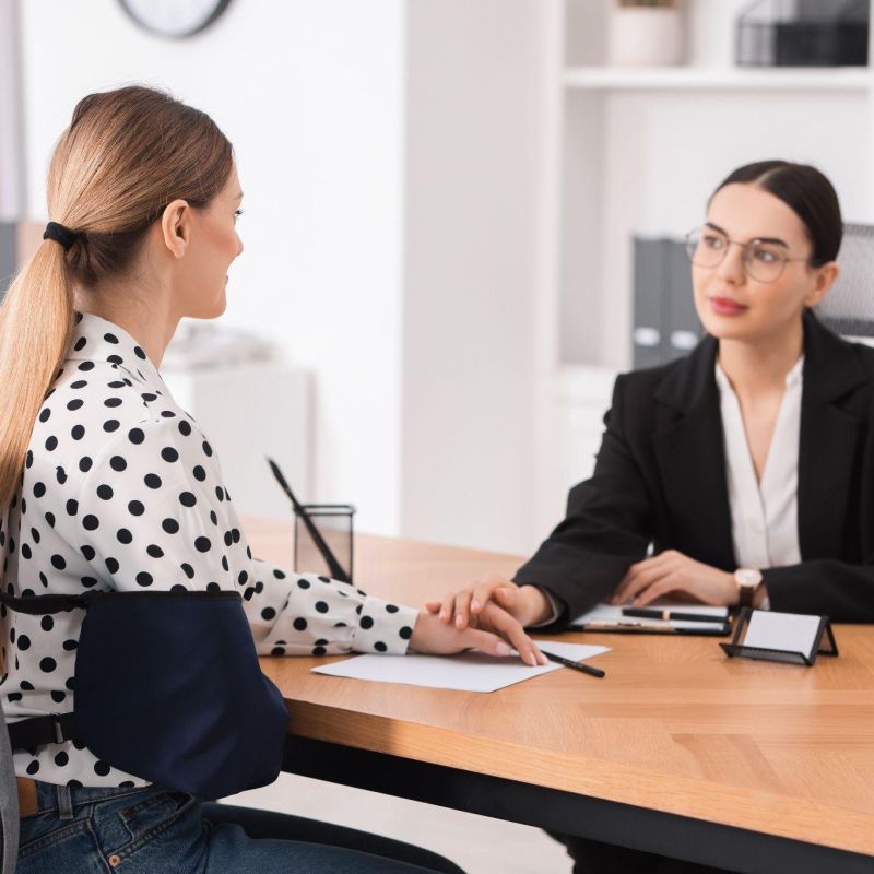 Dos mujeres en una reunión de negocios en una oficina, participando en una conversación de apoyo.