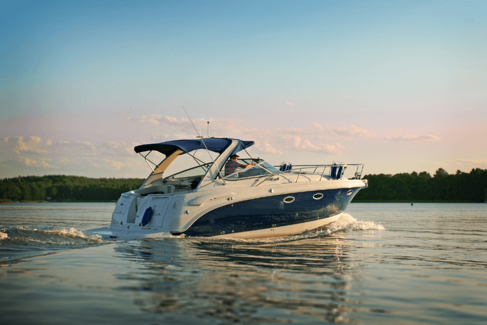 Luxury motorboat cruising on calm lake water during a serene sunset with trees in the background.