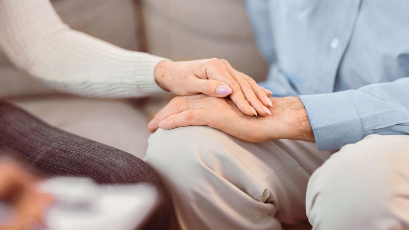 Two people holding hands, symbolizing comfort and support, with a focus on togetherness.