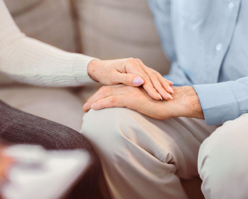 Two people holding hands, symbolizing comfort and support, with a focus on togetherness.