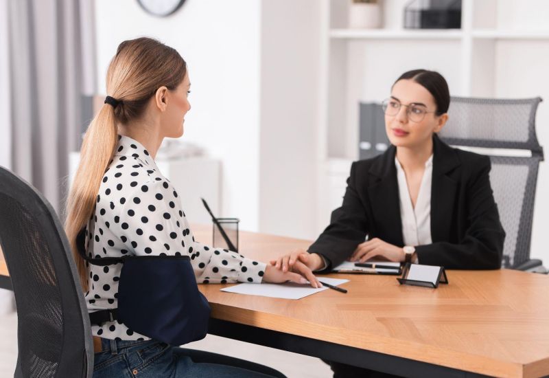 Two women at a business meeting in an office, engaging in a supportive conversation.