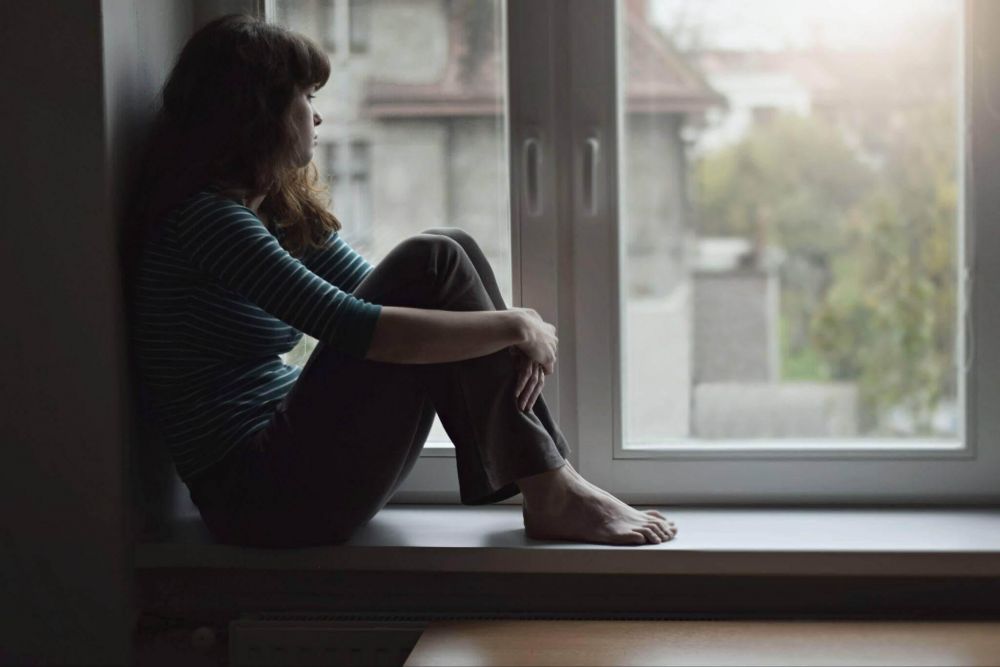 Woman sitting on a windowsill, looking out