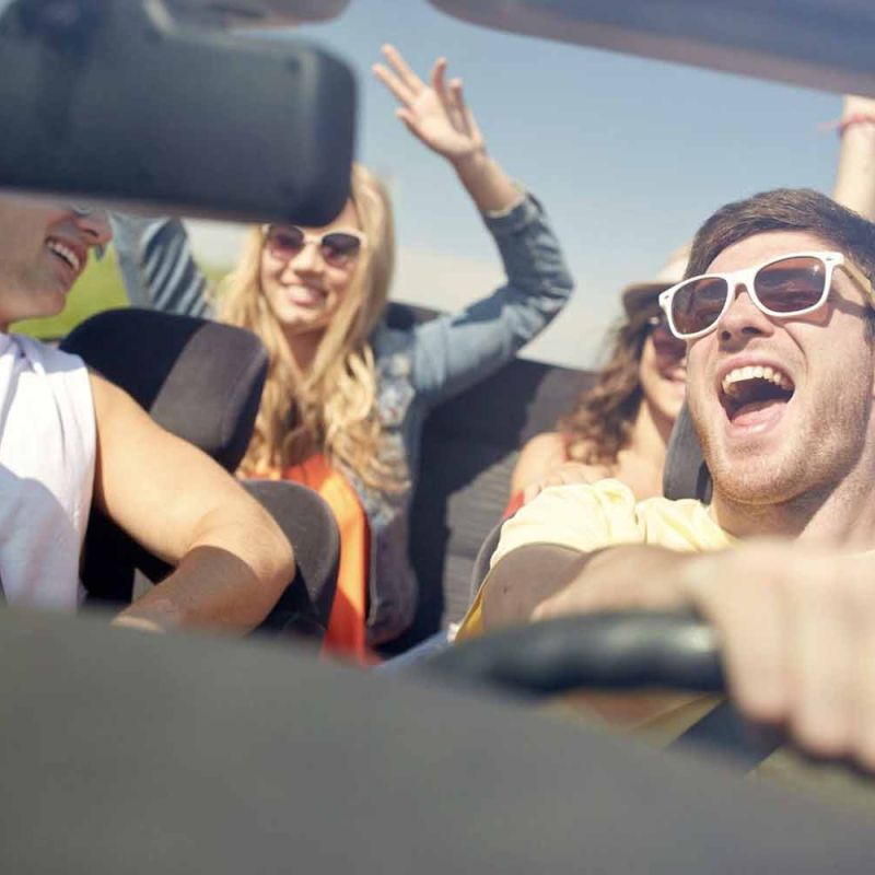 Four teens driving in a convertible having fun, but being very distracting to the young driver