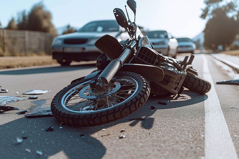 Motorcycle accident scene on road with car in background, illustrating traffic collision aftermath.