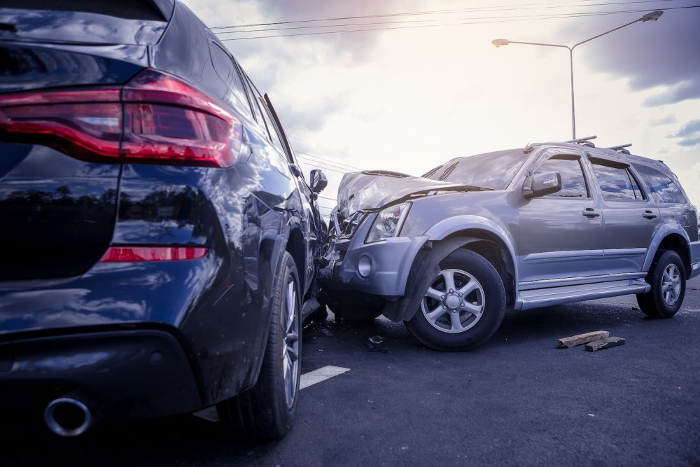 Two SUVs collide on a road, causing significant front-end damage.