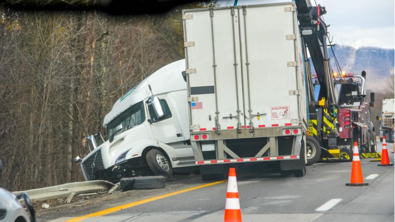 Semi-truck crash being towed after highway accident near wooded area