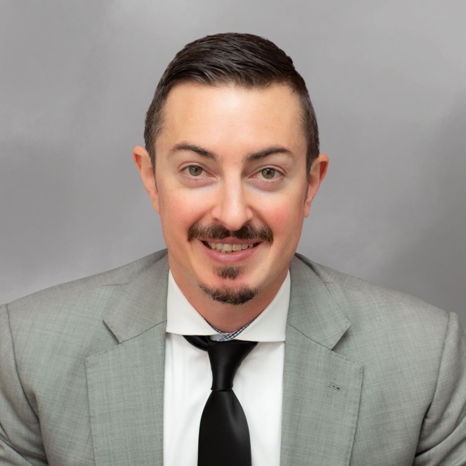 Andrew M. Coffarelli in a suit with shoulder-length hair and a patterned tie, smiling in a portrait