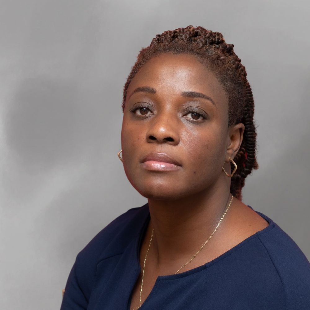 Portrait of Dorothy Braxton in a blue blouse with braided hair against a gray background.