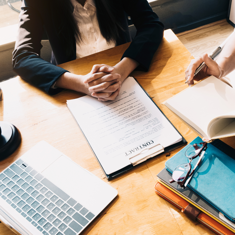 Two people discussing nursing home legal documents at a desk with a laptop, gavel, and books.