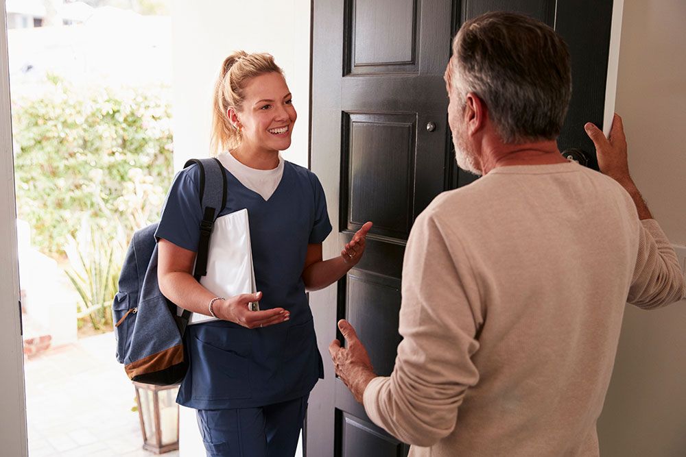 Healthcare professional greeting a senior man at home, providing in-home care services.