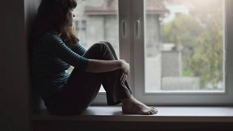 Woman sitting on a windowsill, looking out