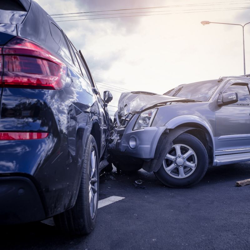 Two SUVs collide on a road, causing significant front-end damage.