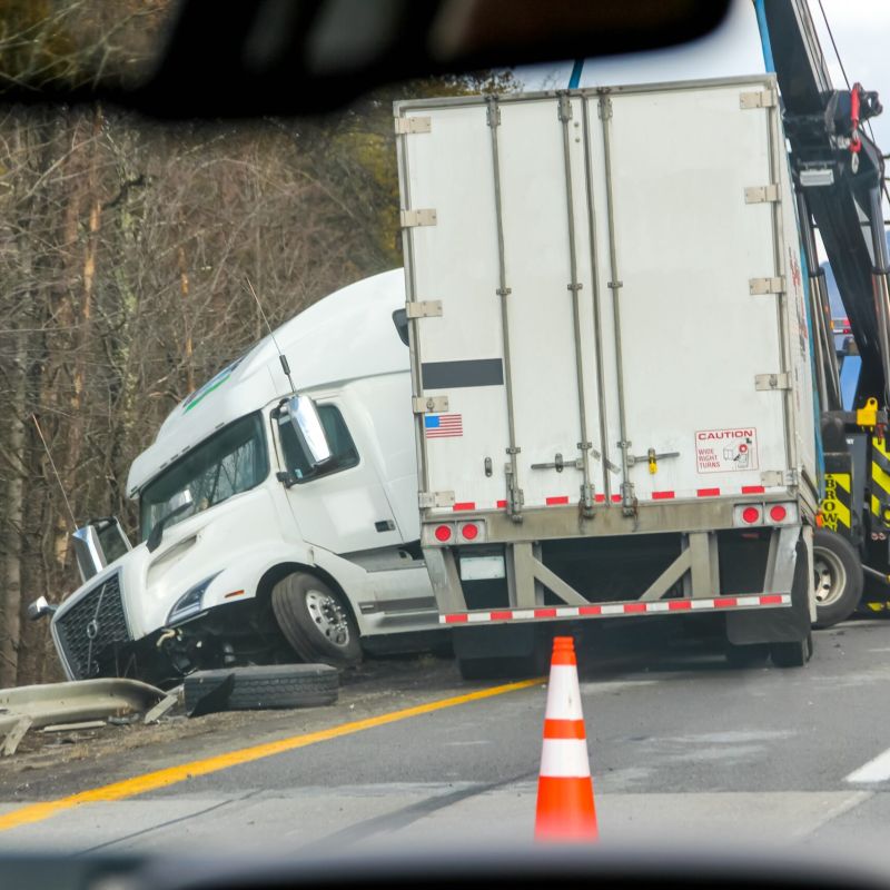 Semi-truck crash being towed after highway accident near wooded area