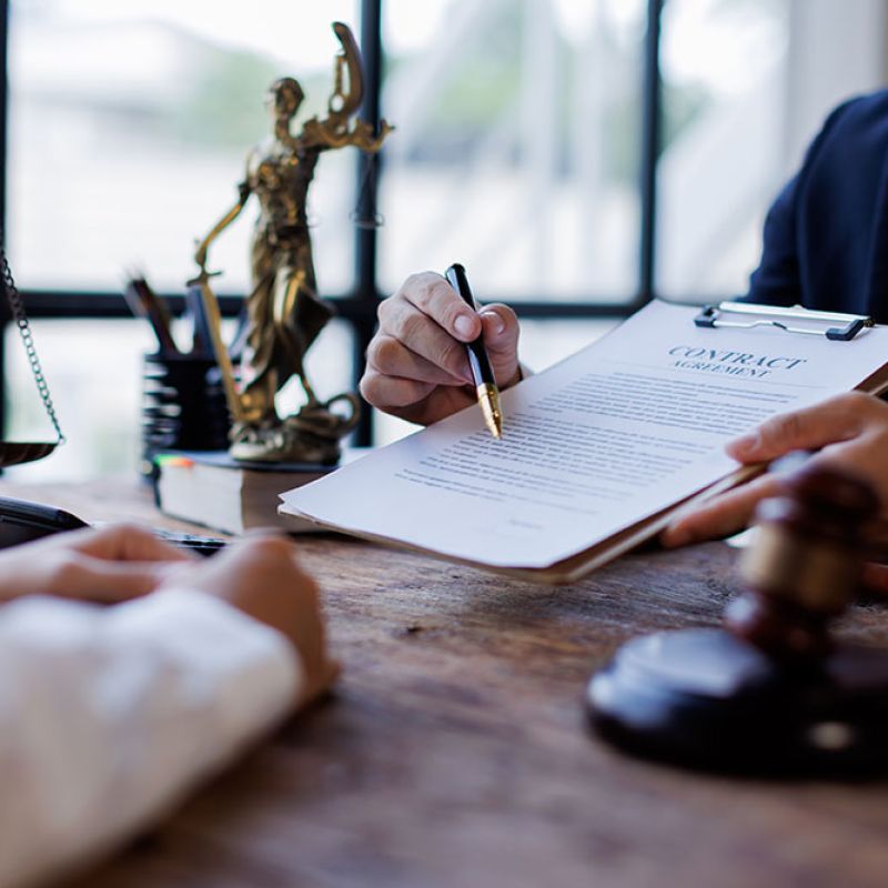 Lawyer reviewing a contract at a desk with scales of justice and gavel, highlighting legal consultation and agreement.