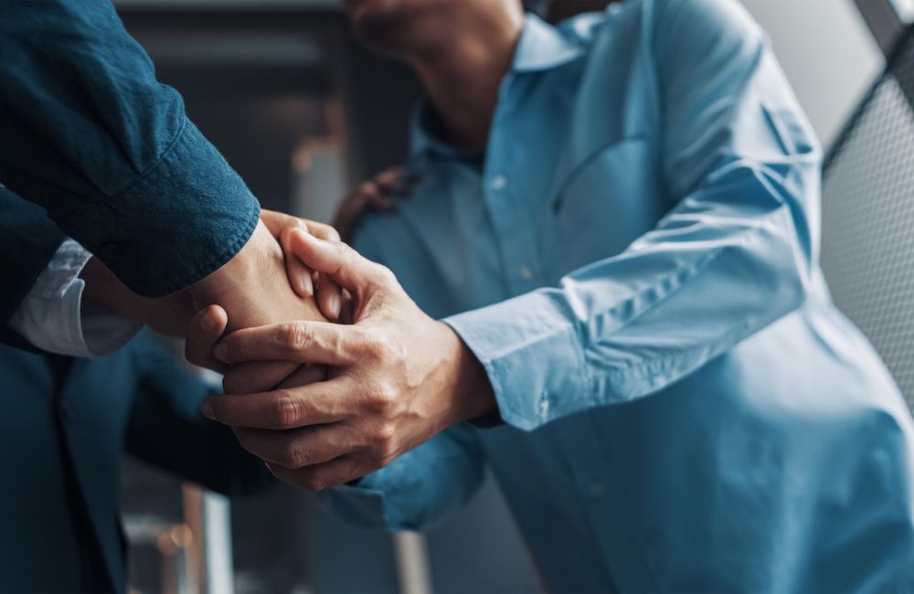 Two people shaking hands, symbolizing business agreement and partnership in a professional setting.