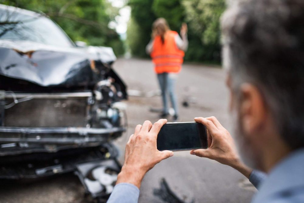 a man taking a picture of a car accident in a public road