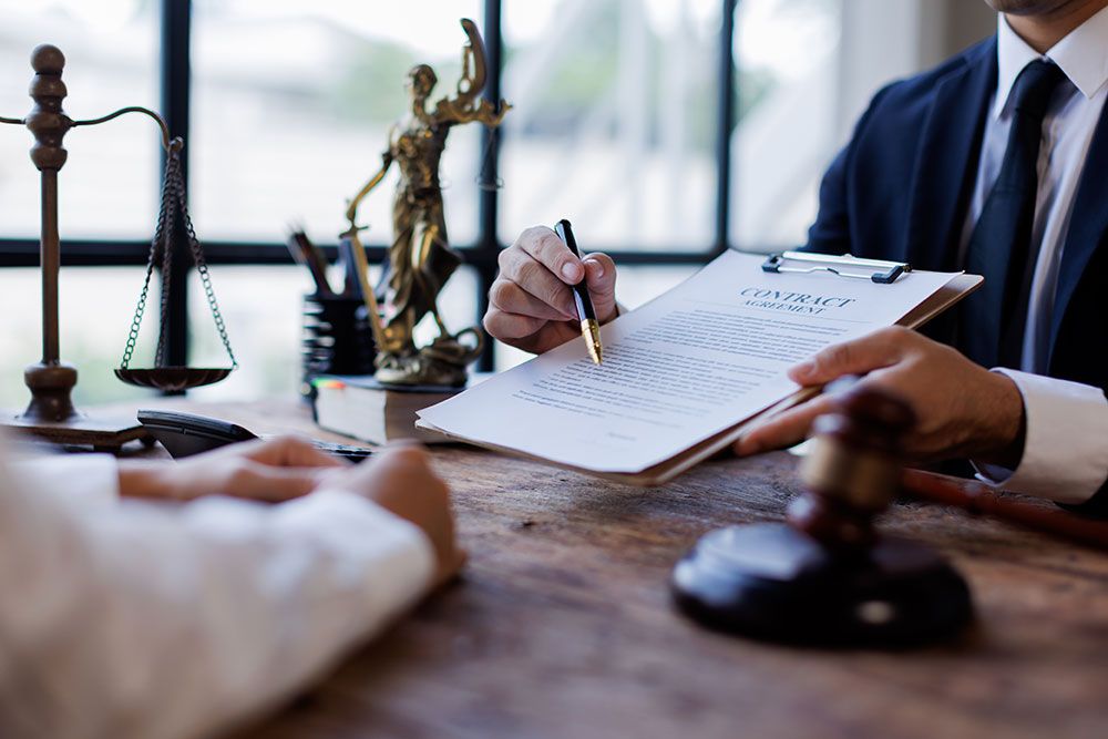 Lawyer reviewing a contract at a desk with scales of justice and gavel, highlighting legal consultation and agreement.