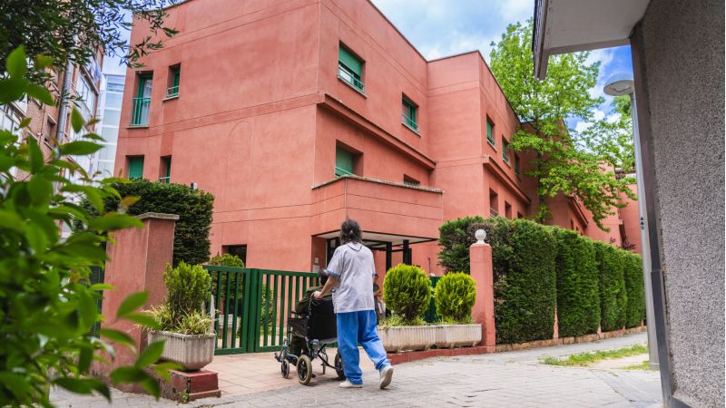 Caregiver pushing elderly resident in wheelchair outside nursing home; Williams DeLoatche handles nursing home abuse cases.