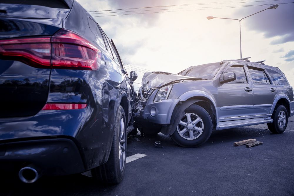 Two SUVs collide on a road, causing significant front-end damage.