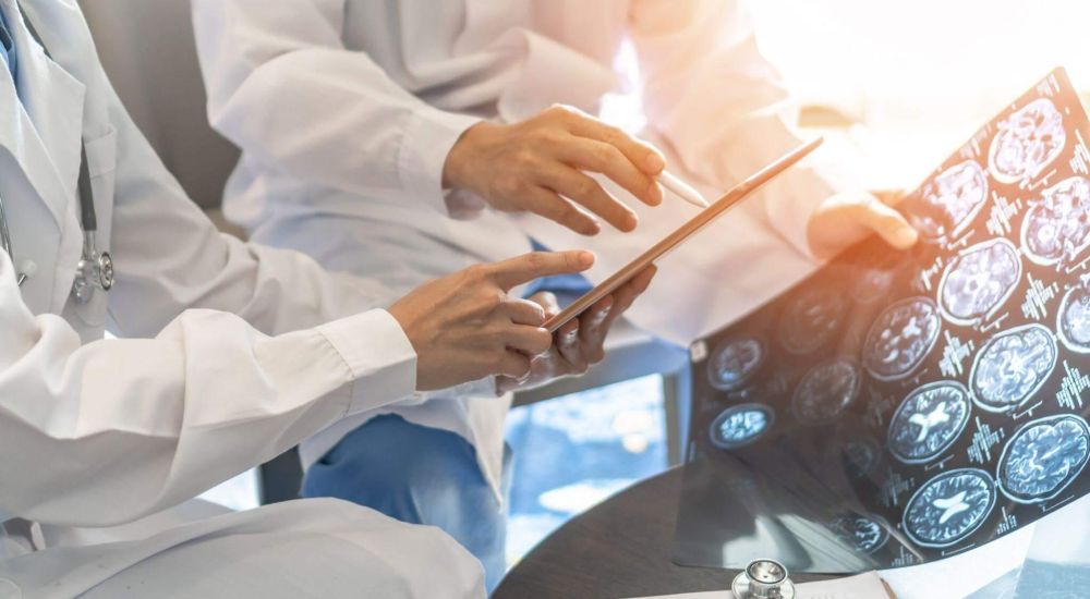 a group of doctors sitting around a table looking at a tablet