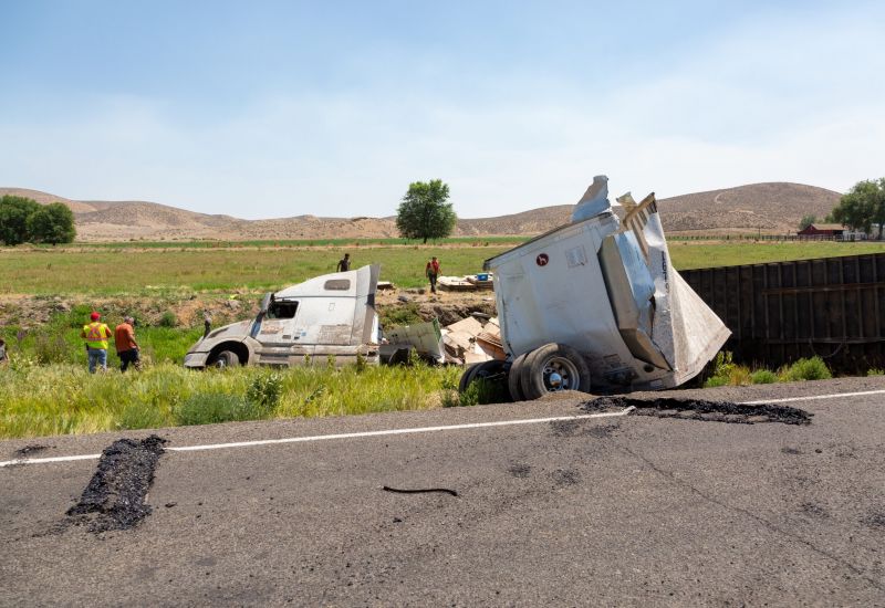 Overturned semi-truck and damaged trailer off rural highway, aftermath of a trucking accident