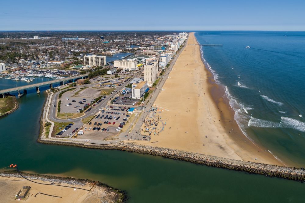 Aerial view of Virginia Beach oceanfront, showing sandy beach, ocean waves, and hotels lining the shore.