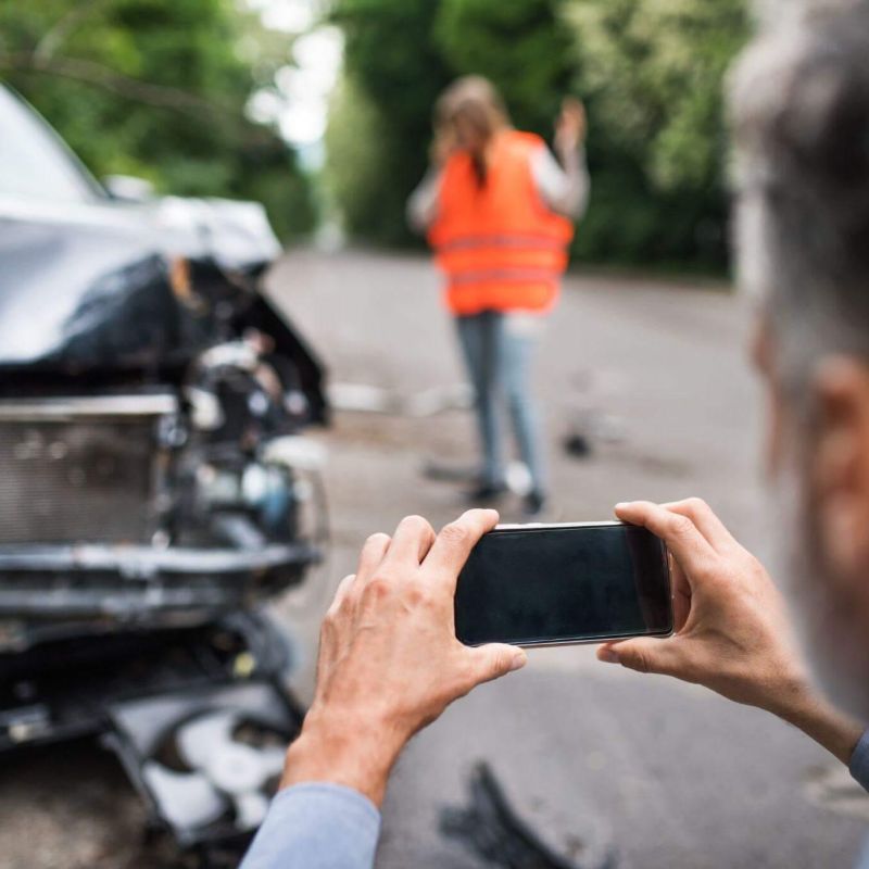 a man taking a picture of a car accident in a public road