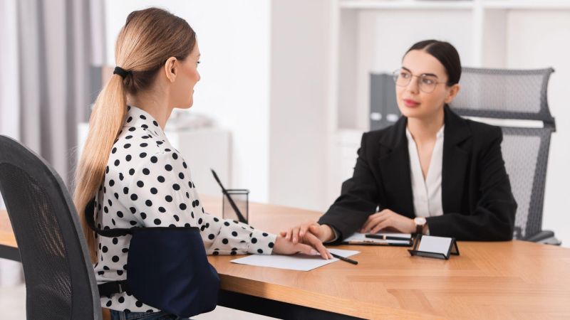Two women at a business meeting in an office, engaging in a supportive conversation.