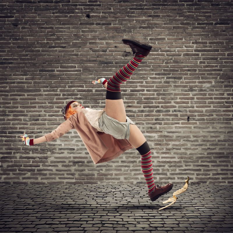 Funny clown slips on a banana peel. concept of unlucky