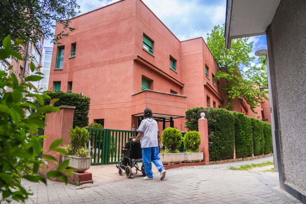 Caregiver pushing elderly resident in wheelchair outside nursing home; Williams DeLoatche handles nursing home abuse cases.