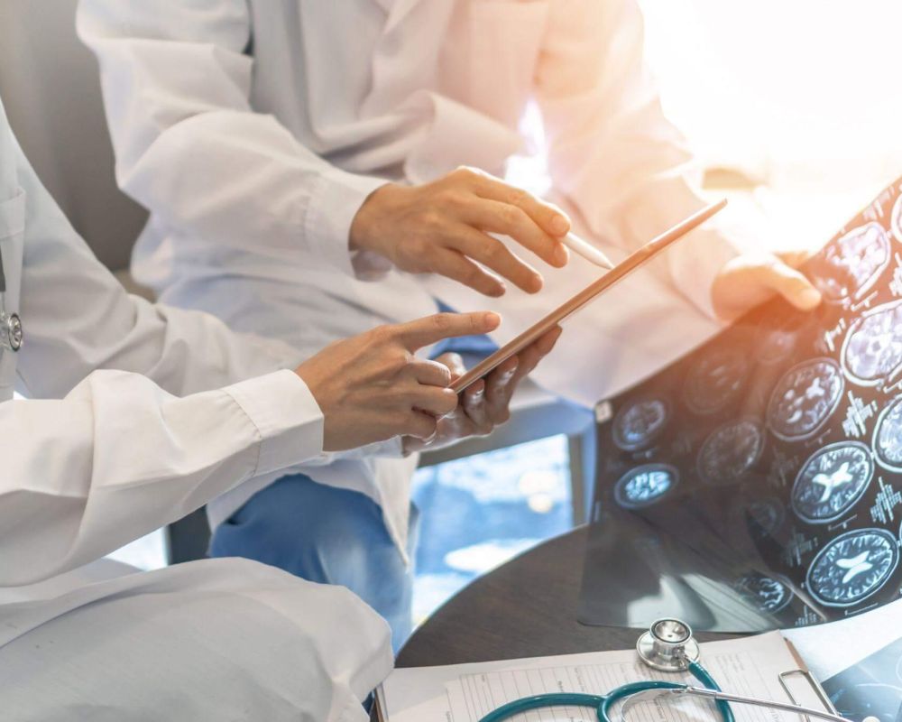 a group of doctors sitting around a table looking at a tablet
