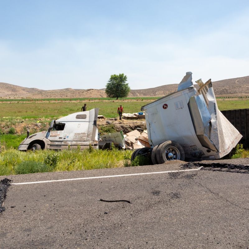 Overturned semi-truck and damaged trailer off rural highway, aftermath of a trucking accident
