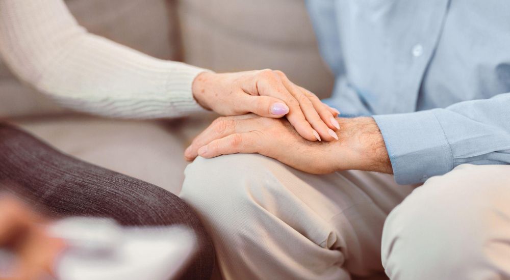 Two people holding hands, symbolizing comfort and support, with a focus on togetherness.