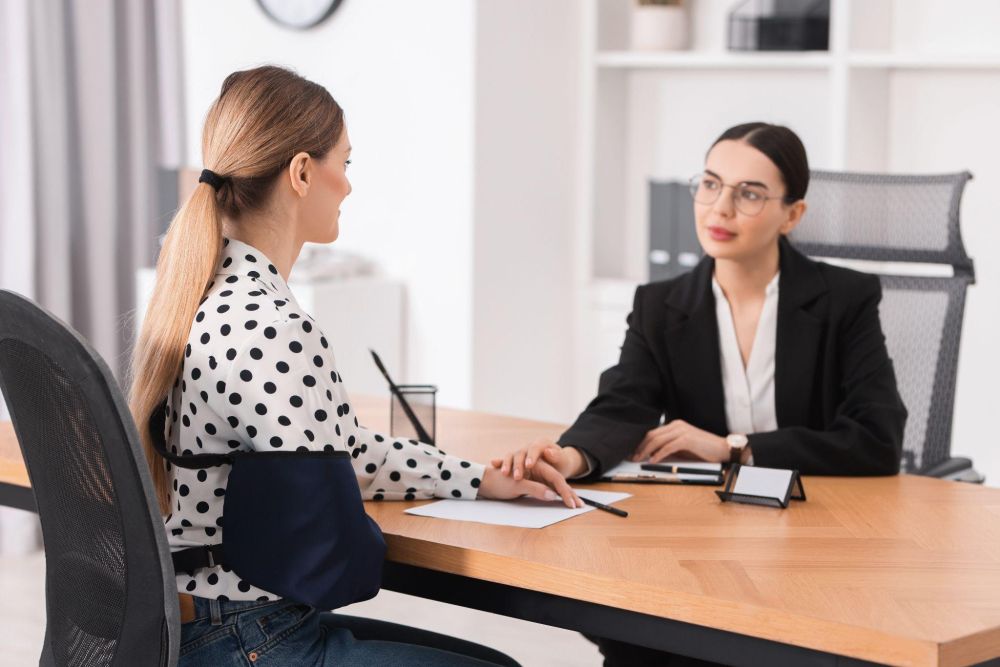 Two women at a business meeting in an office, engaging in a supportive conversation.