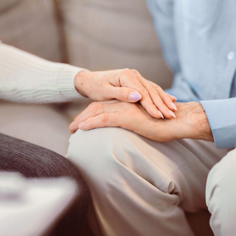 Two people holding hands, symbolizing comfort and support, with a focus on togetherness.