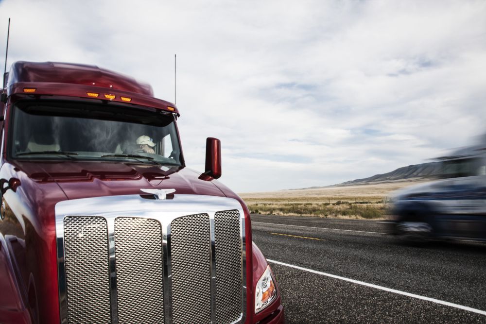 Two semi-trucks pass closely on rural highway, highlighting risk factors in a trucking accident