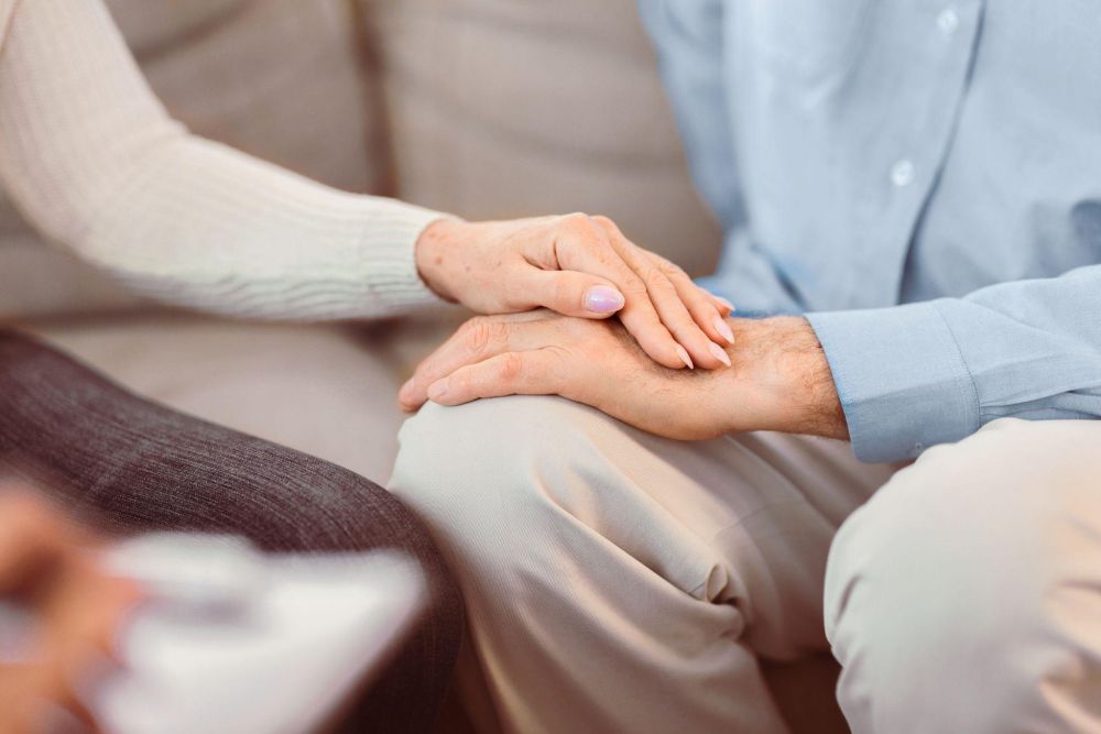 Two people holding hands, symbolizing comfort and support, with a focus on togetherness.