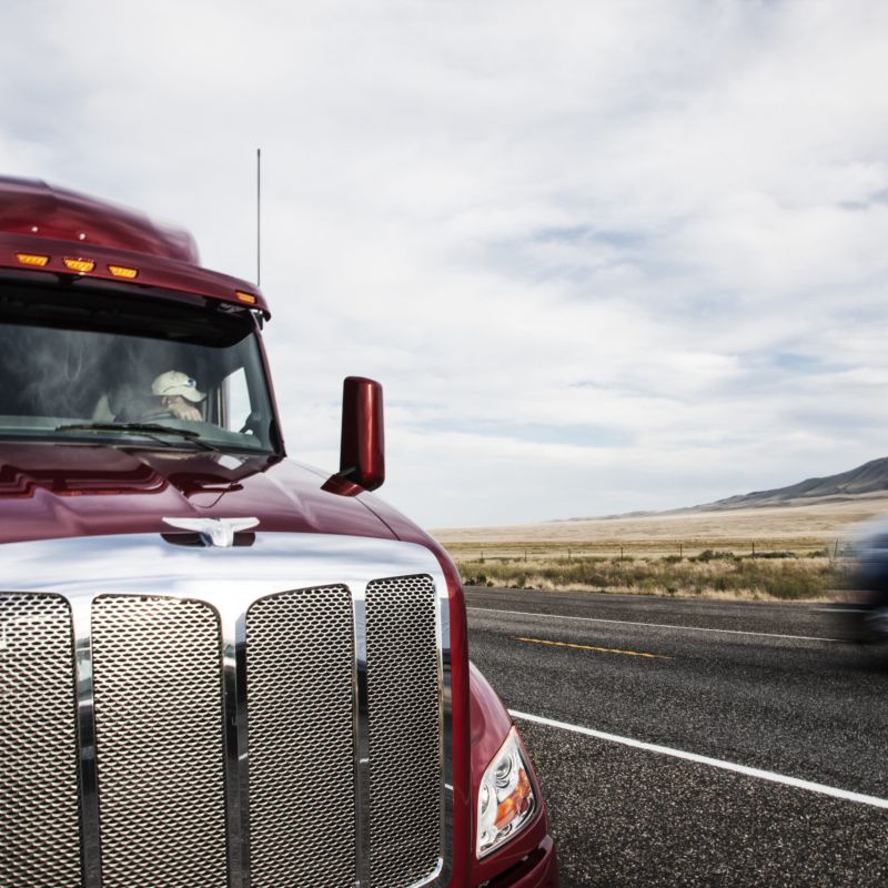 Two semi-trucks pass closely on rural highway, highlighting risk factors in a trucking accident