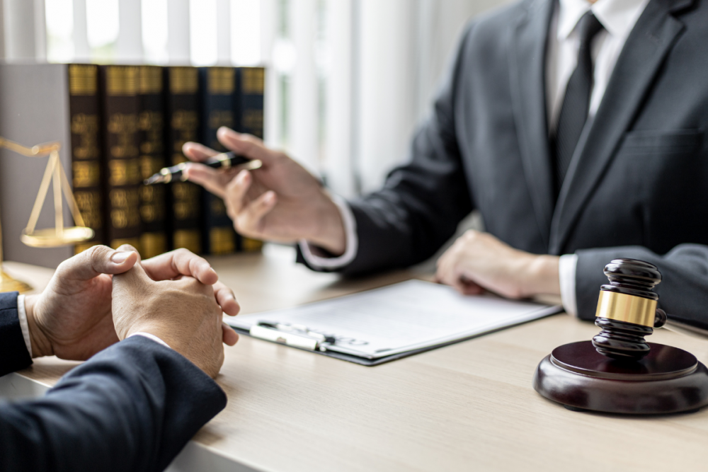 Lawyer advising client with legal documents and gavel on desk, symbolizing legal consultation and justice.