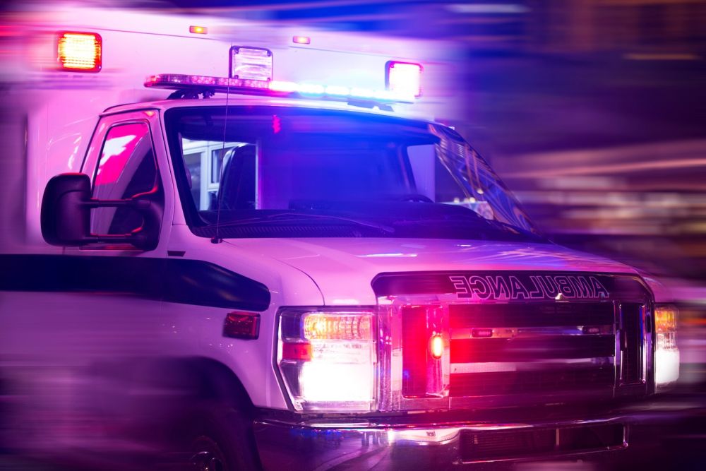 Emergency ambulance with flashing lights on a city street at night.