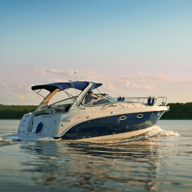 Luxury motorboat cruising on calm lake water during a serene sunset with trees in the background.