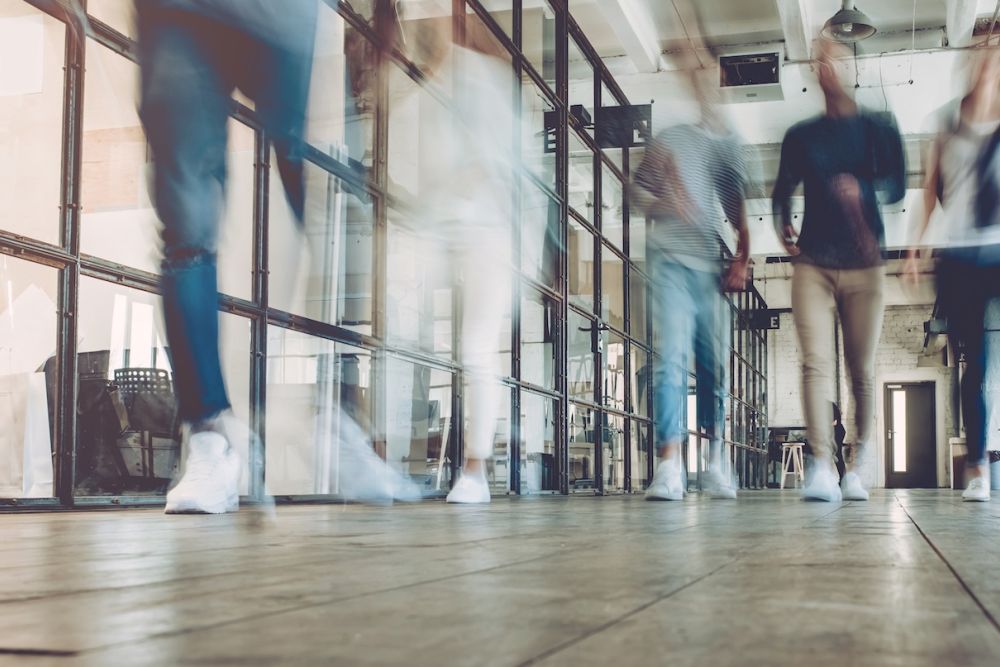 Blurred people walking in modern office hallway, showcasing dynamic work environment and collaboration.