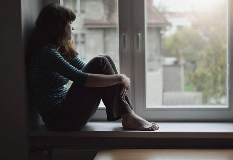 Woman sitting on a windowsill, looking out