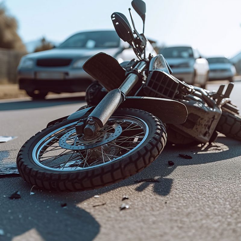 Motorcycle accident scene on road with car in background, illustrating traffic collision aftermath.