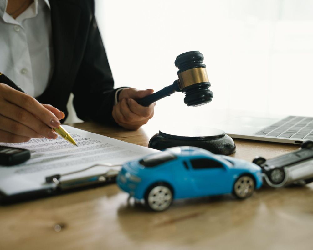 Lawyer reviewing car accident case documents with gavel and toy car, emphasizing legal expertise in auto claims.