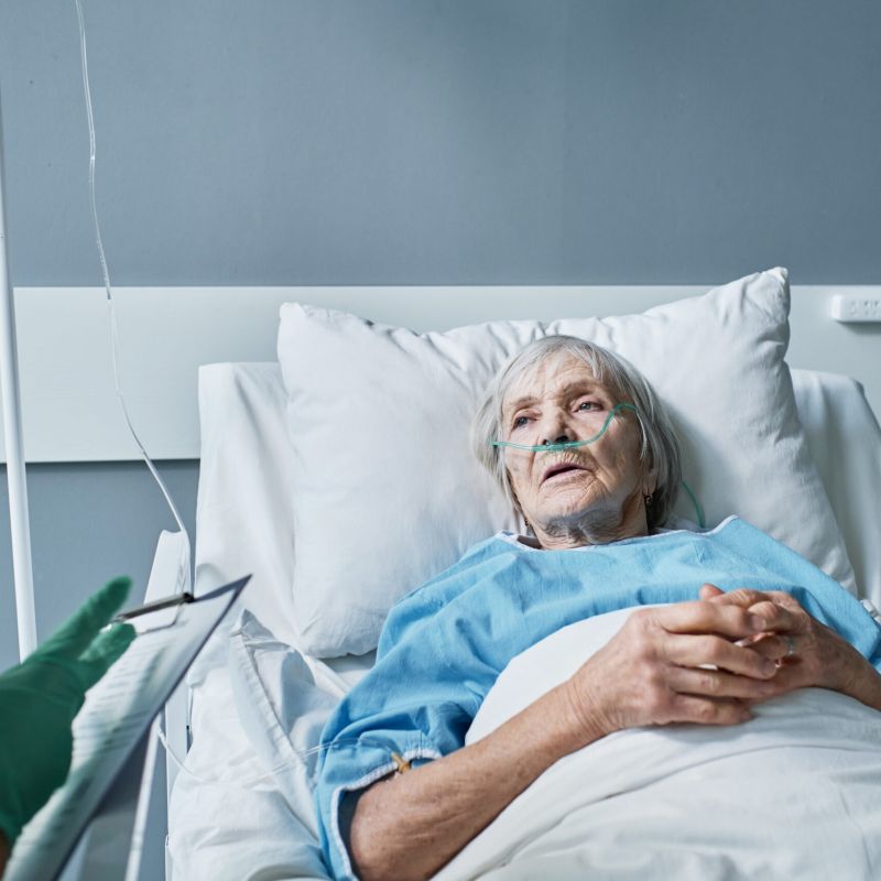 Elderly woman in hospital bed speaking with doctor, illustrating pressure ulcer risks and long-term care concerns.