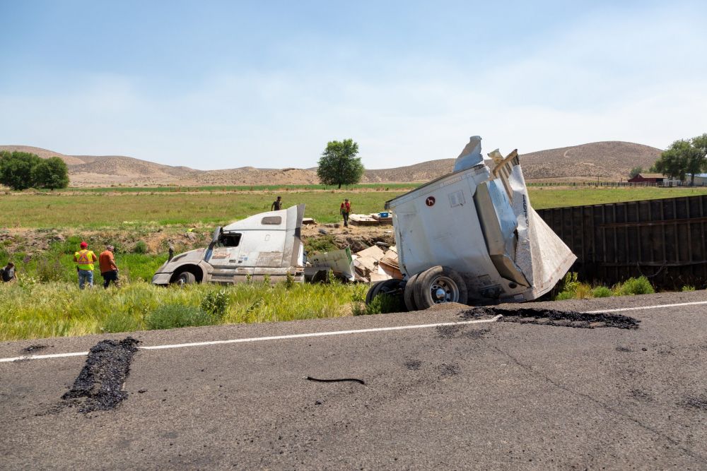 Overturned semi-truck and damaged trailer off rural highway, aftermath of a trucking accident