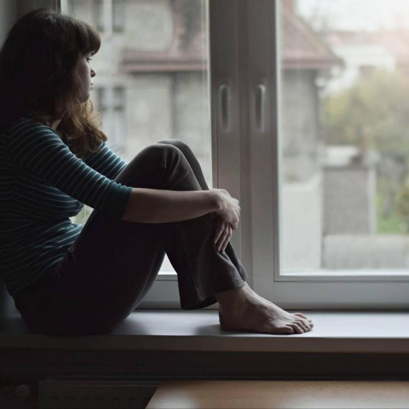 Woman sitting on a windowsill, looking out