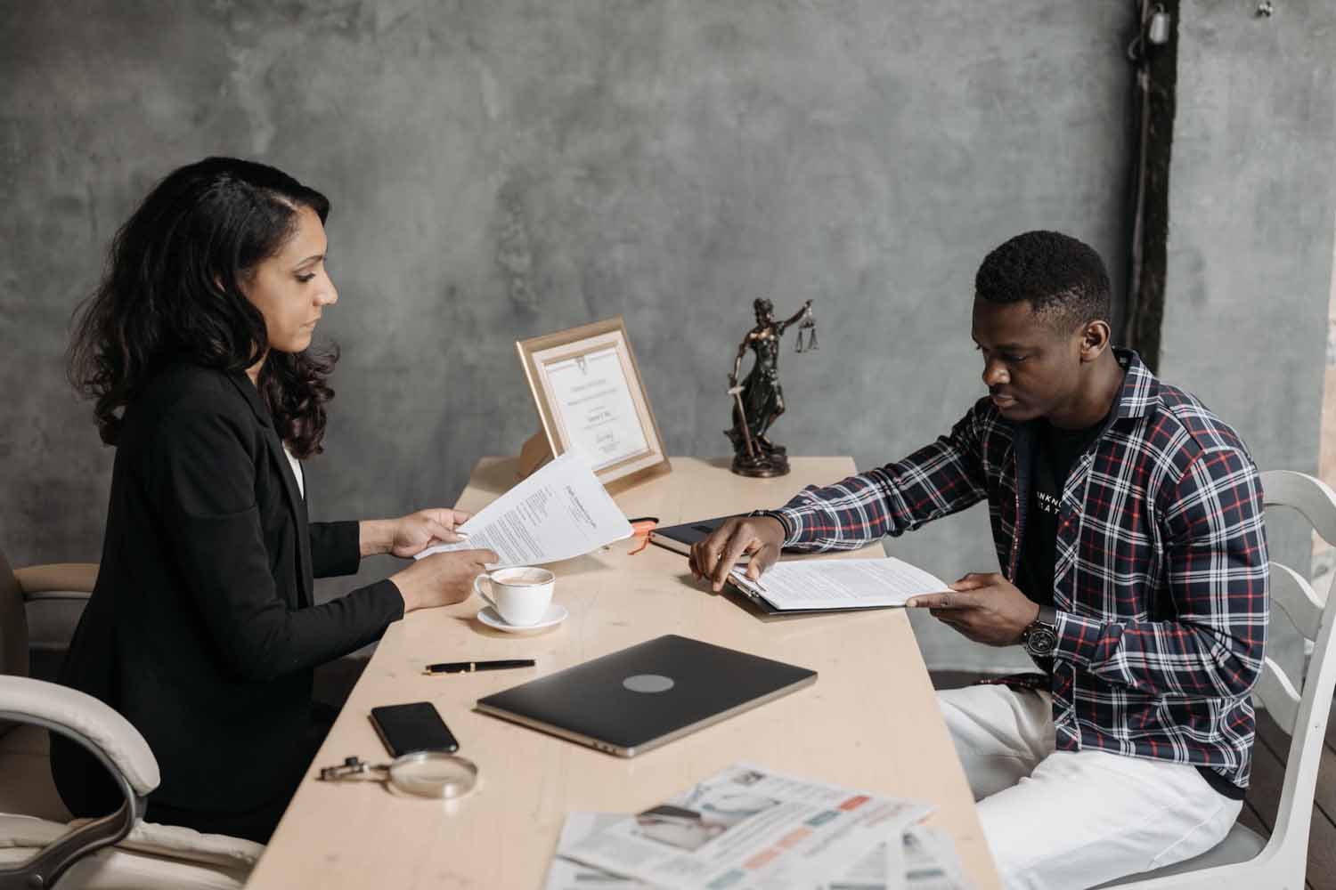 Man in plaid shirt sits at a desk with a female attorney, looking over paperwork