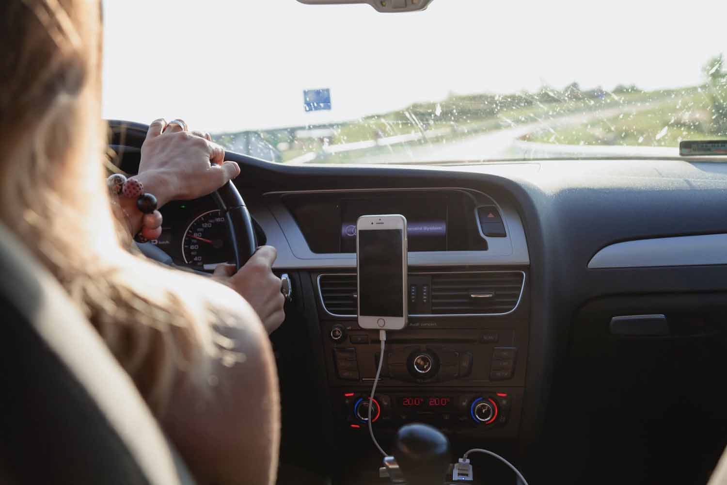 Teen girl driving while her cell phone is connected to the car’s hands-free system